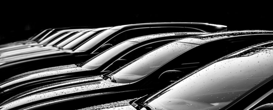 Black and white image of brand new cars in a row at a dealership.