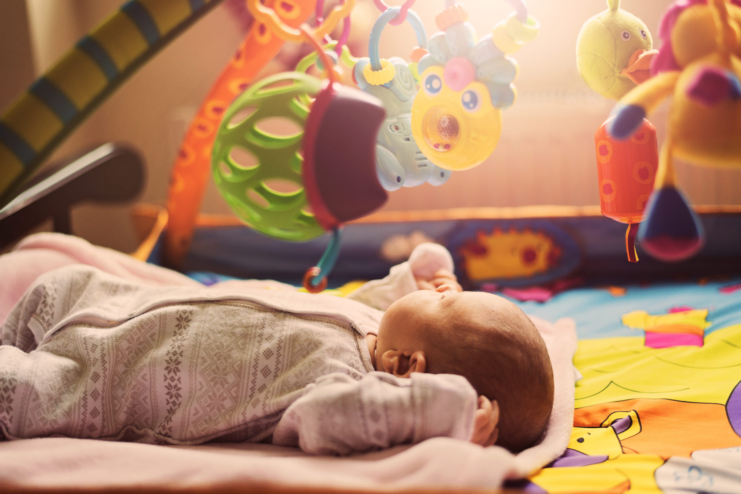 Infant playing inside of an activity gym.