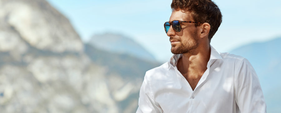 Man wearing ray-ban style sunglasses, standing on a villa.